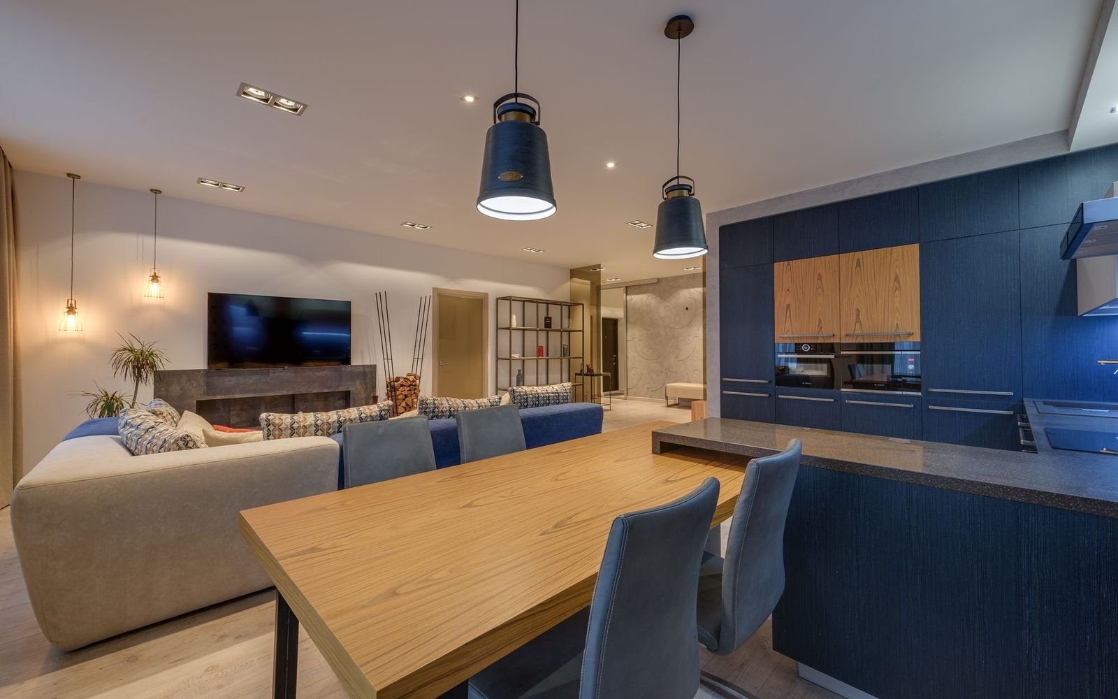 Open-plan living room with a dining table and a blue kitchen after a kitchen renovation