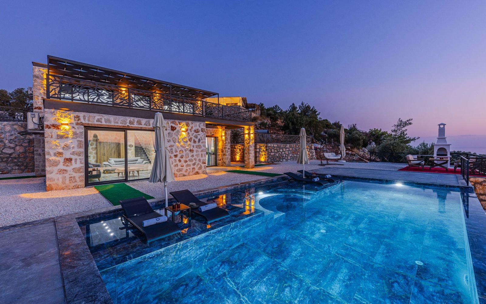 Stone villa with a lit swimming pool at dusk, where pool lighting and outdoor electrics need regular checks